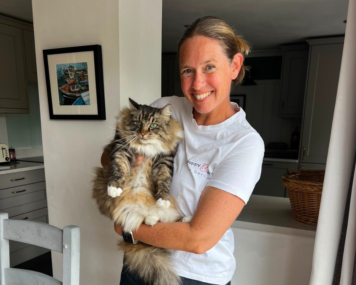 Sue in her Happy Bunny t-shirt holding a long-haired tabby cat at home
